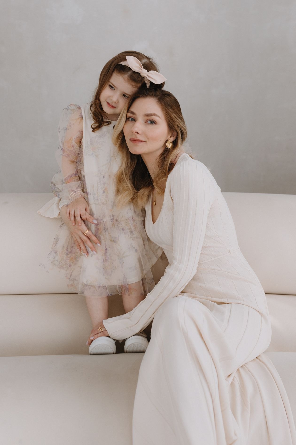 Mother and daughter standing together in elegant dresses